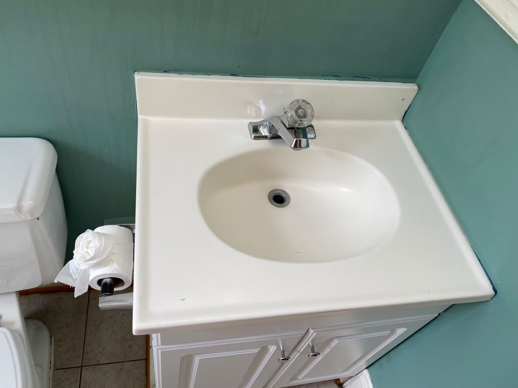 Clean pedestal sink and sage-green bathroom after cleaning